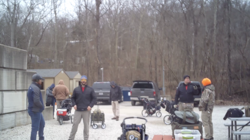 People standing near gear at the shooting range in the cold.
